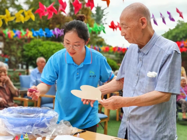 长者在工作人员指导下制作漆扇