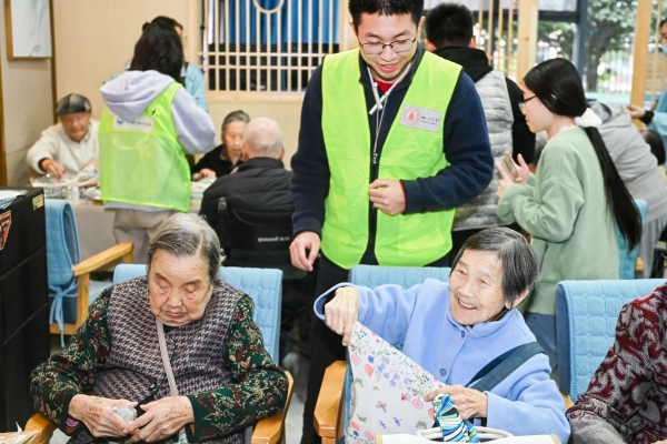 四川大学志愿者陪同长者做手工包